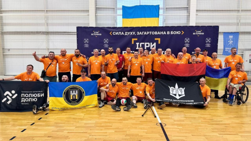 На фото зображені ветерани на фоні банеру "Ігри ветеранів"