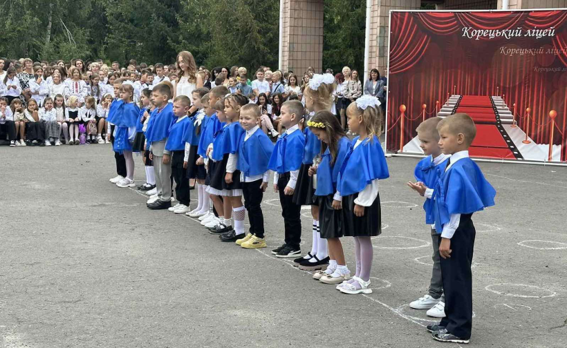 Першокласники стоять на лінійці: вони святково одягнені та посміхаються