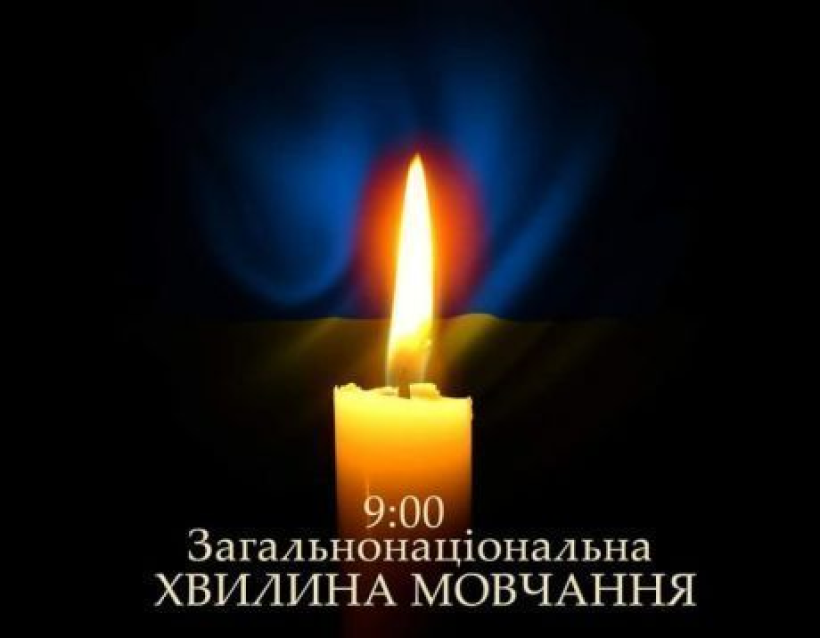 На фото зображено свічку на фоні державного прапору України