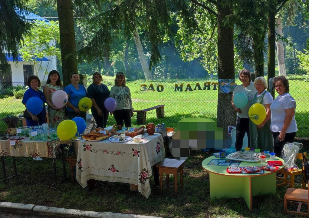 Біля столів стоять усміхнені жінки - працівники дитячого садочка "Малятко".