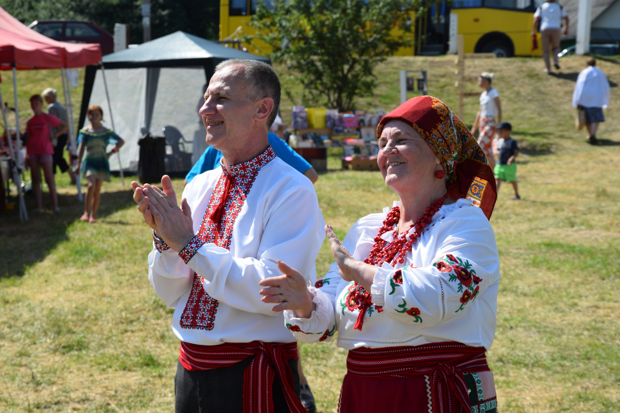 Двоє працівників закладів культури Городоцької громади в українських костюмах аплодують та посміхаються