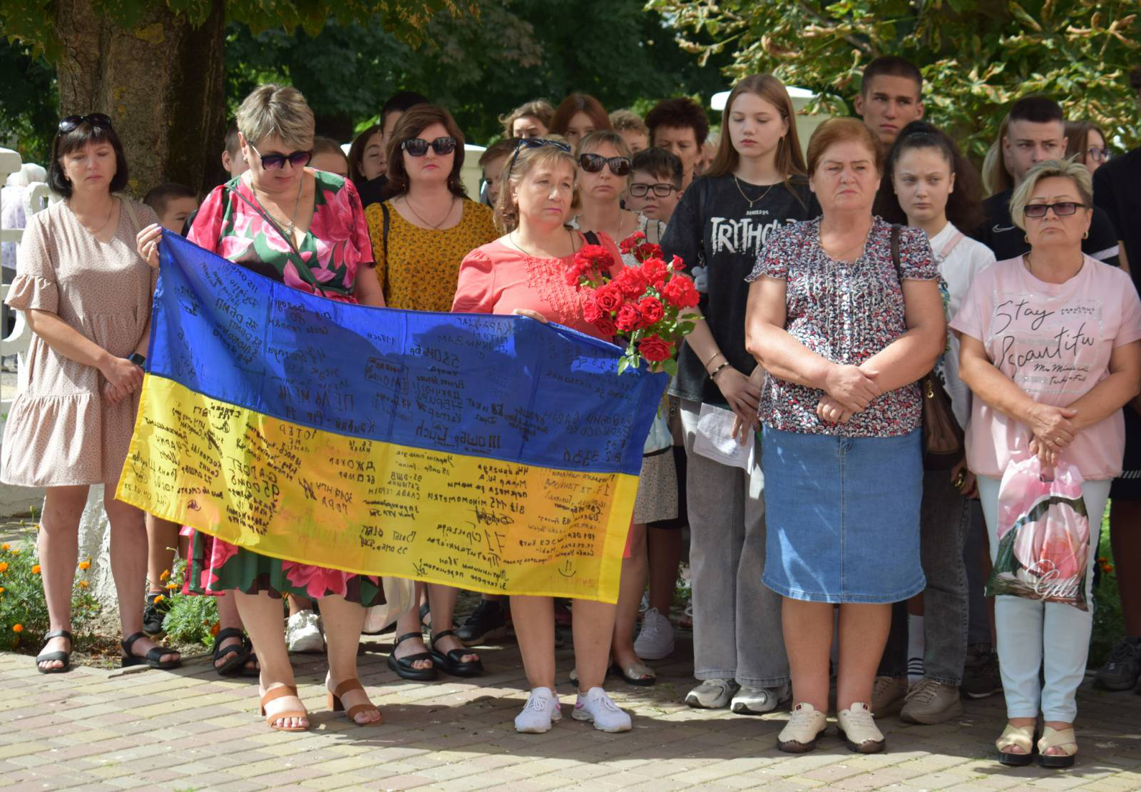 Учасники мітингу з нагоди відкриття меморіальної дошки Олександру Дещинському тримають у руках квіти та жовто-блакитний прапор